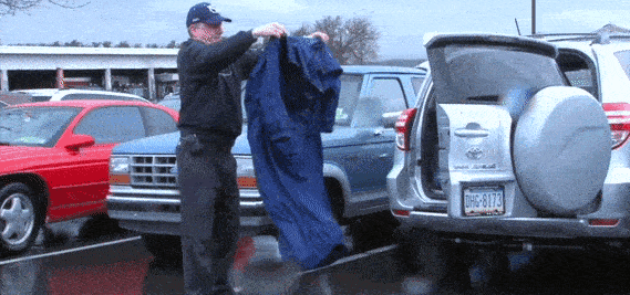 Rolling the IWOM Convertible Waterproof Jacket up and putting in car at tailgate.