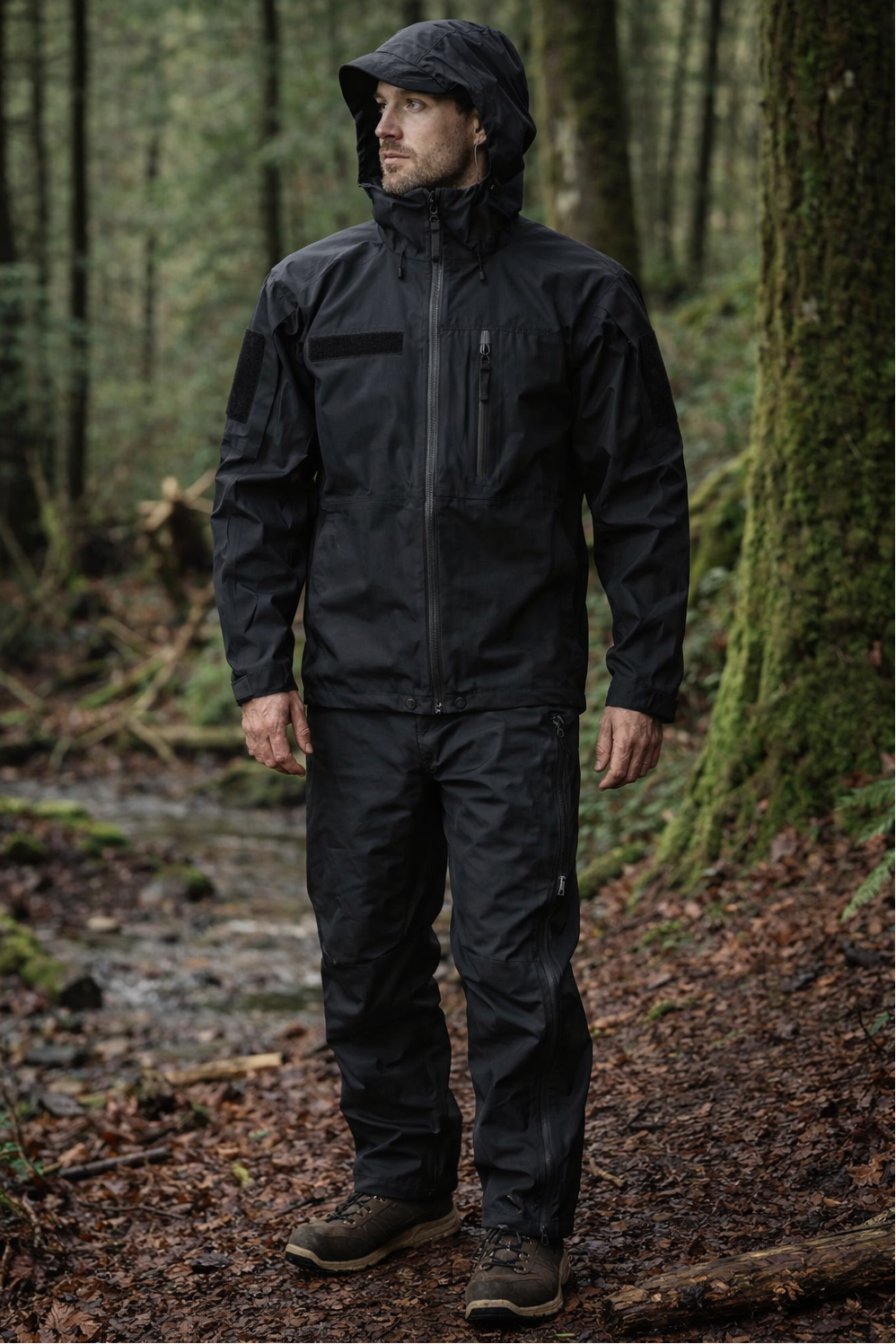 Person wearing a black raincoat and pants standing in a forest