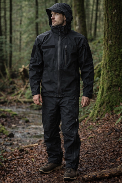 Person wearing a black raincoat and pants standing in a forest